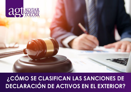 ¿Cómo se Clasifican las Sanciones de Declaración de Activos en el Exterior? Abogdao FIrmando Documento con Mazo Legal Al Frente