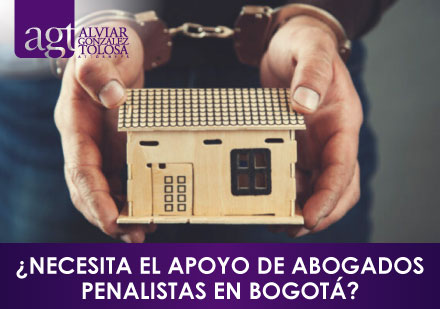 ¿Necesita el Apoyo de Abogados Penalistas en Bogotá? Hombre Esposado con Casa de Juguete en las Manos